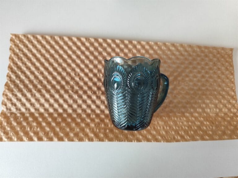 Szklany kubek ustawiony na arkuszu papieru bąbelkowego kraftowego